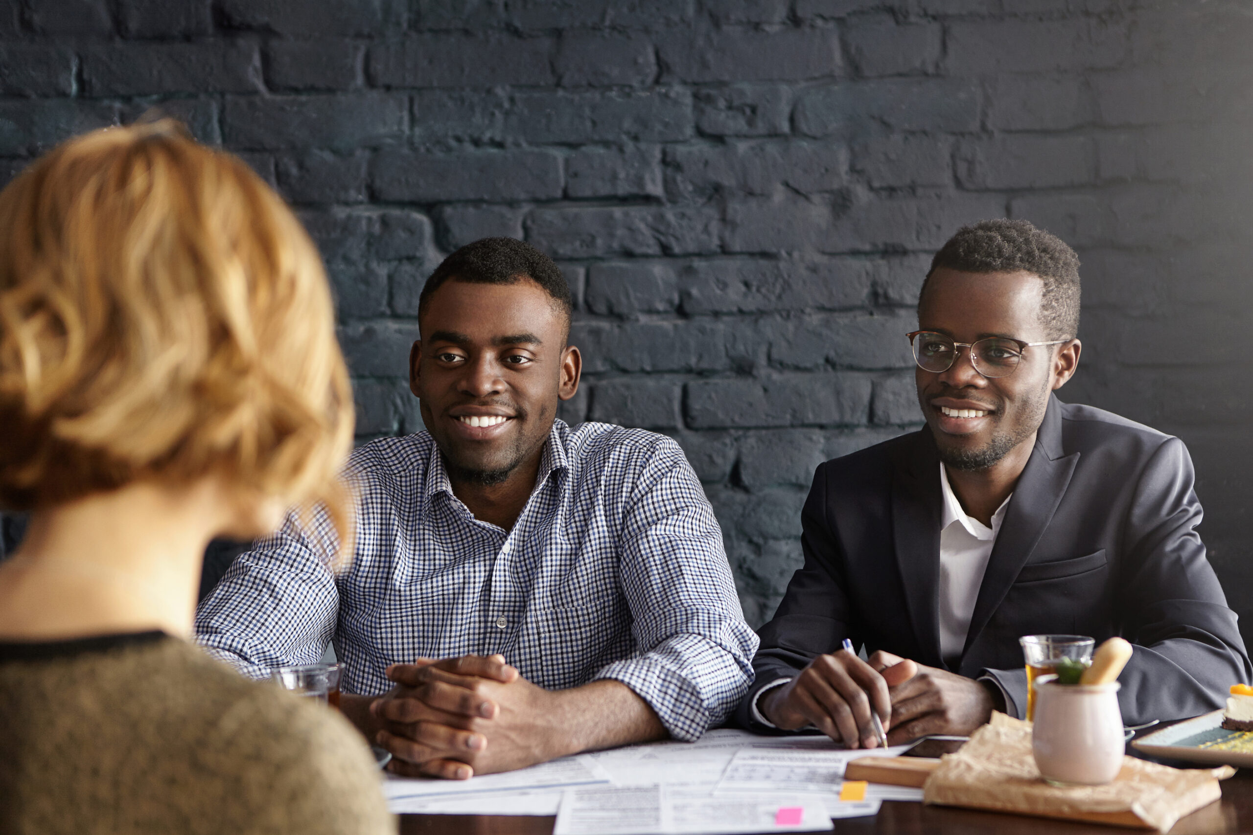 Caucasian female candidate being interviewed for position in office during job interview. Two African-American recruiters asking tricky questions, looking at applicant with interest, smiling happily Caucasian female candidate being interviewed for position in office during job interview. Two African-American recruiters asking tricky questions, looking at applicant with interest, smiling happily