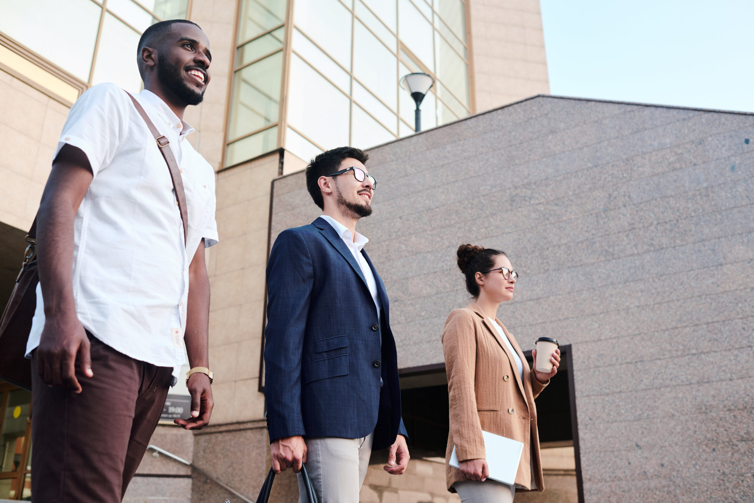Below view of determined business school students standing in row against university and planning career